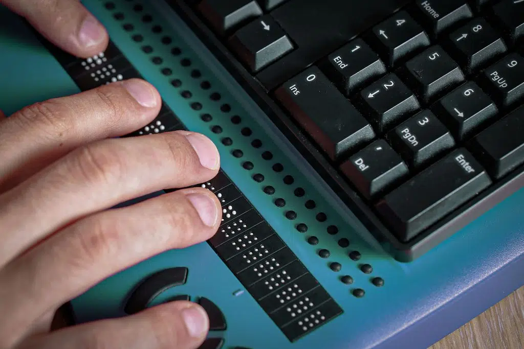 Hand liest eine Braillezeile vor einer Computertastatur, Symbolbild für Barrierefreiheit im Web